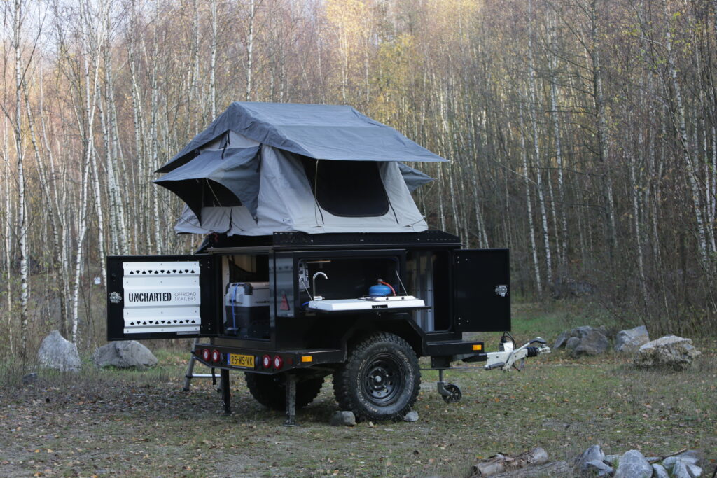 Offroad Camping Trailer with Rooftop tent and kitchen is being displayed.